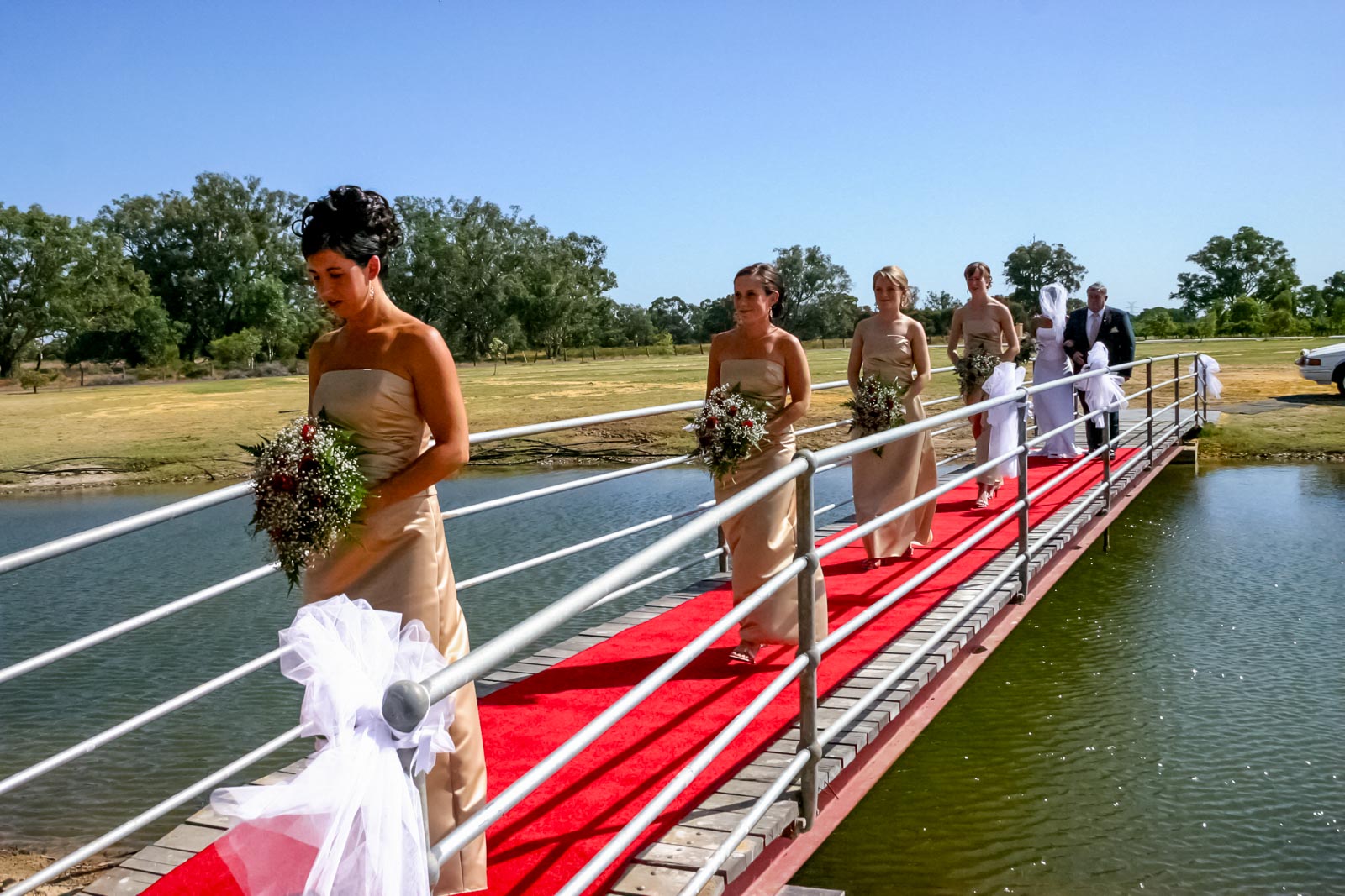 Megs and her bridemaids walk across a bridge to their wedding.