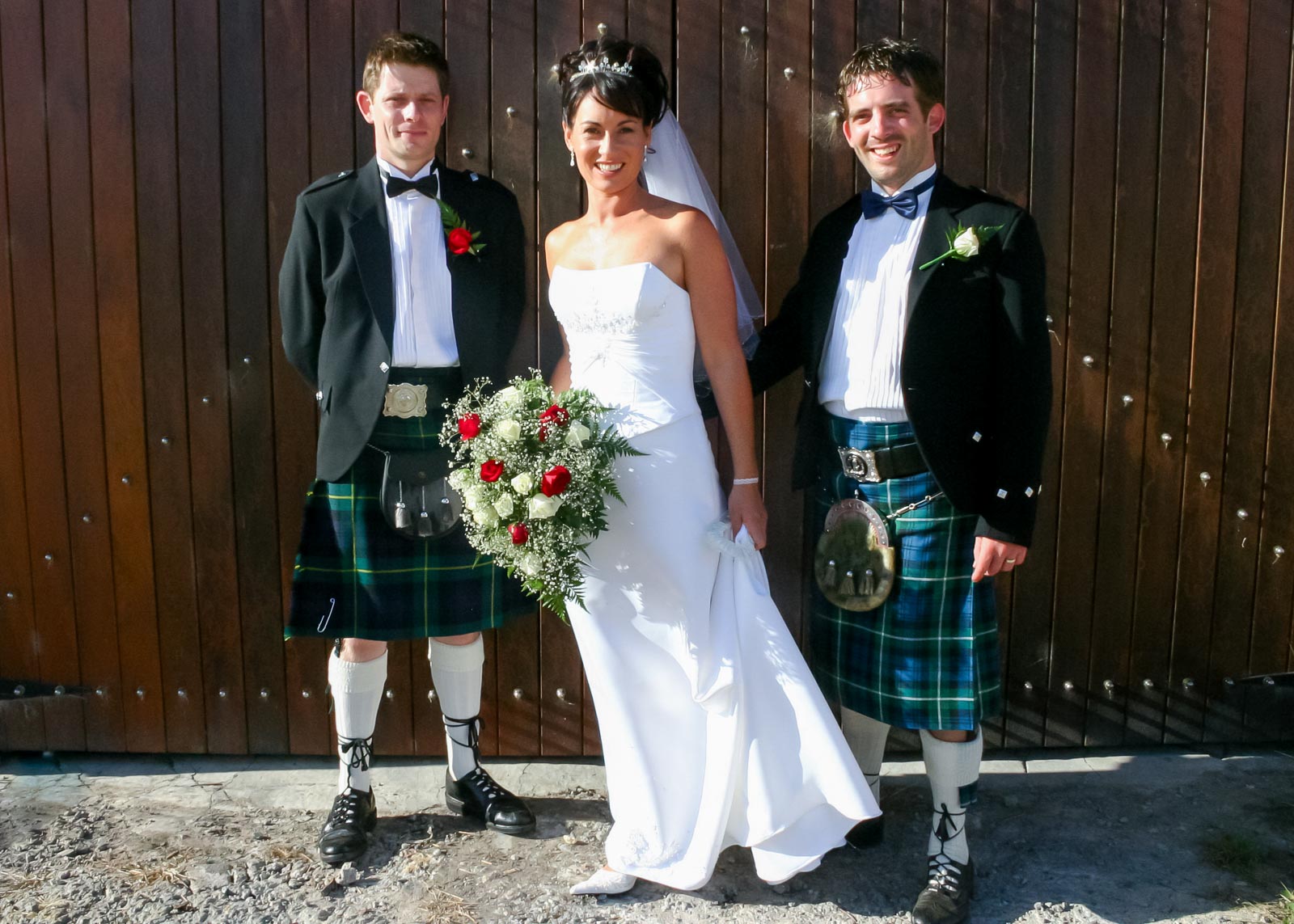 Russ, Megs and the best man pose on front of barn doors.