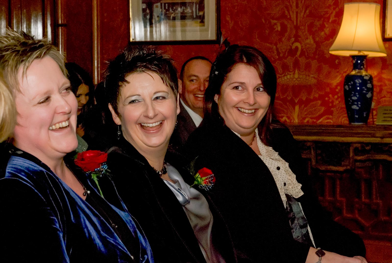 Laura and Paula laugh surrounded by guests inside Brighton Dome before their civil partnership.