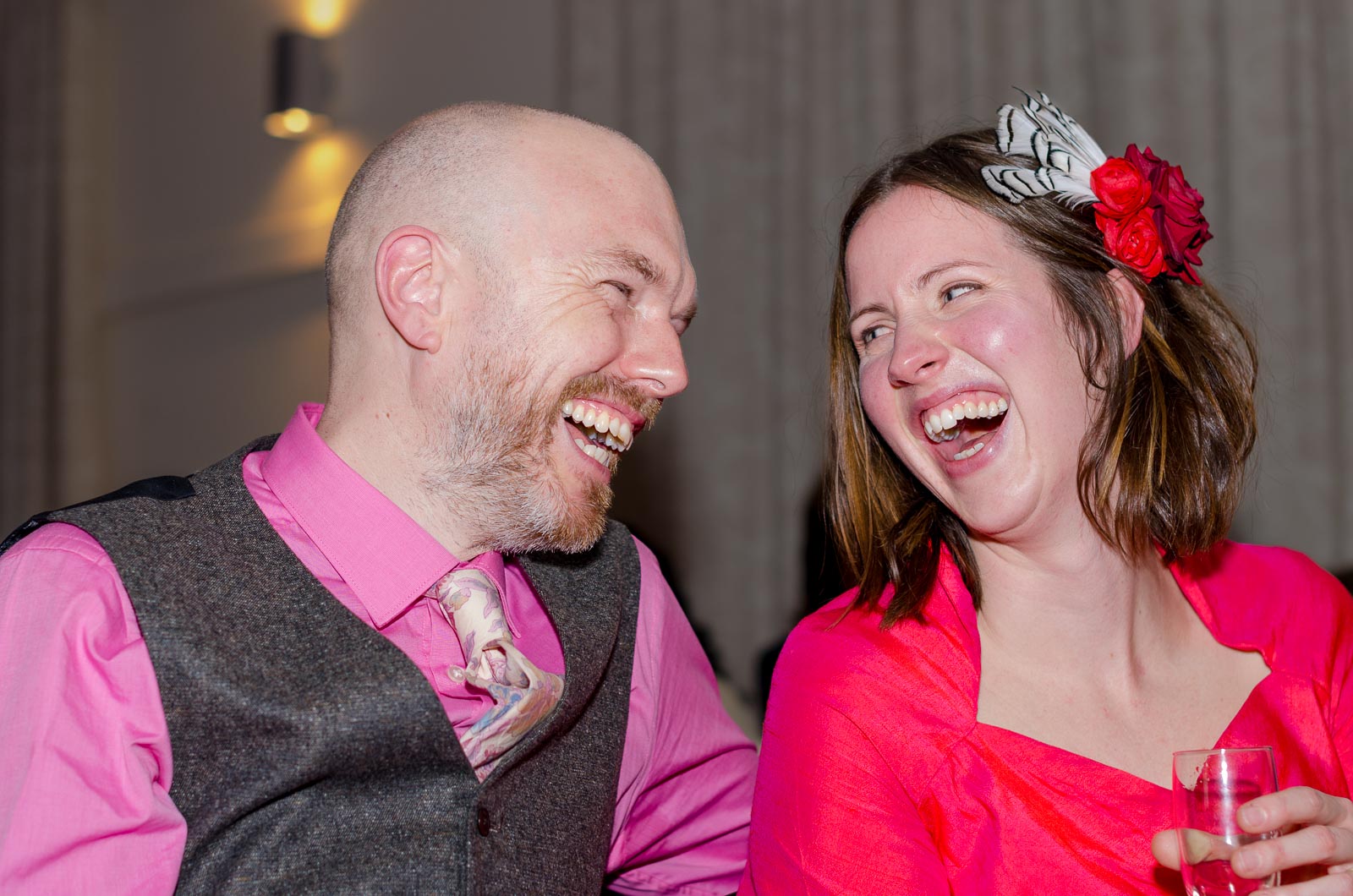 Annie and Mark laugh after their wedding on front of guests in Firle Village Hall.