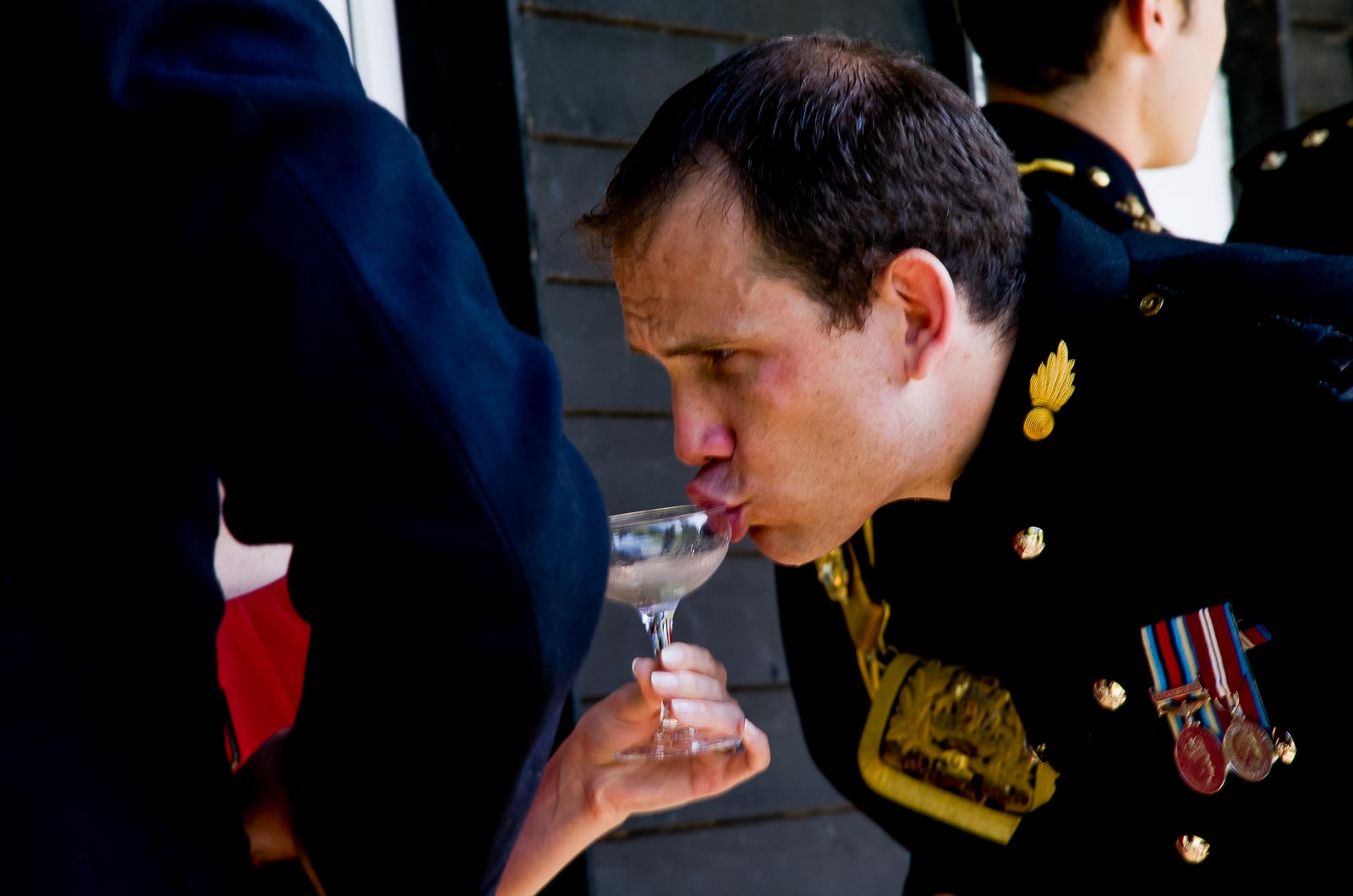 A wedding guest sips champagne at Rachael and Dan's wedding reception at Burpham Village Hall.