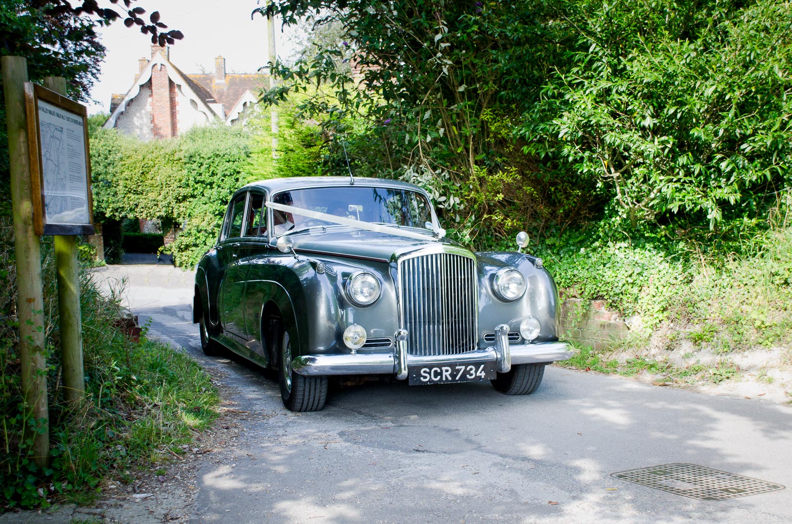 Rachael and Dan arrive at their wedding reception at Burpham Village Hall in a vintage Rolls Royce.