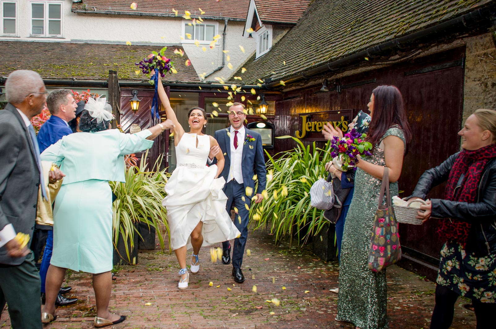 Tash and Raf walk through confetti after their wedding in Borde Hill, Haywards Heath.