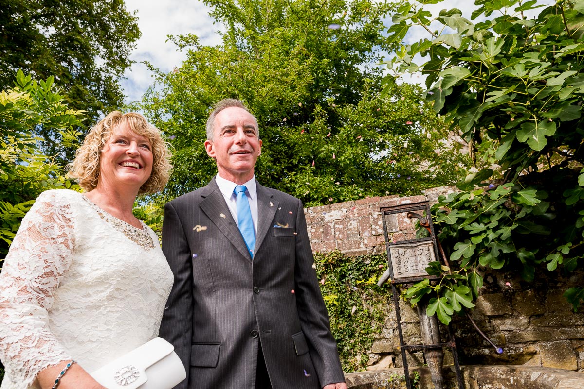 Wendy and Chris smile surrounded by confetti in Southover Grange after their wedding at lewes Register Office.