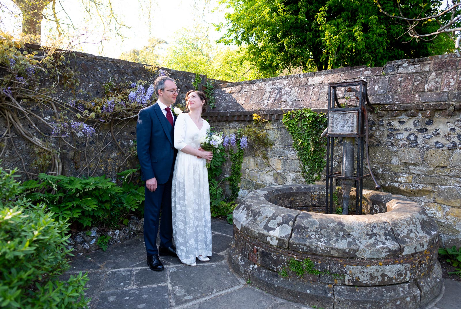 Alexis and Niell look at eachother at the ancient well in Southover Grange, Lewes after their wedding.