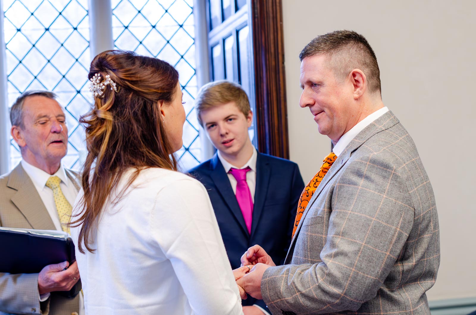 Grant look up at Jane while placing on her wedding ring in the Evelyn Room at Lewes Register Office.