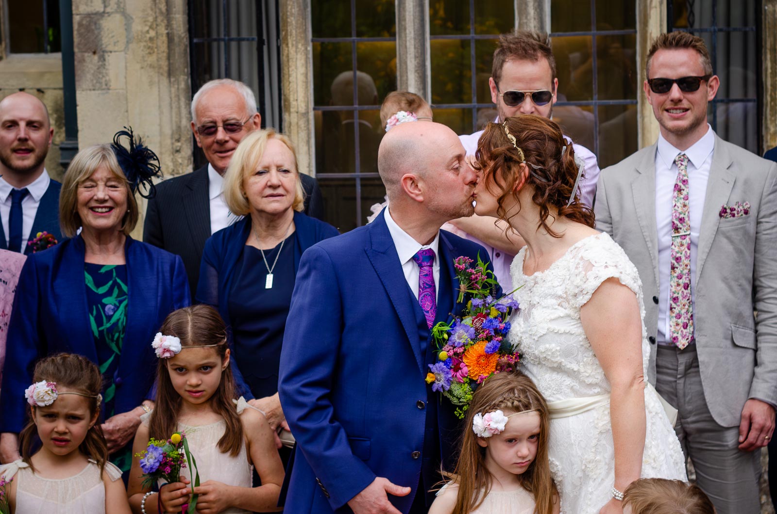 Katherine and Ben kiss outside the back entrance of Lewes Register Office on front of their wedding guests.
