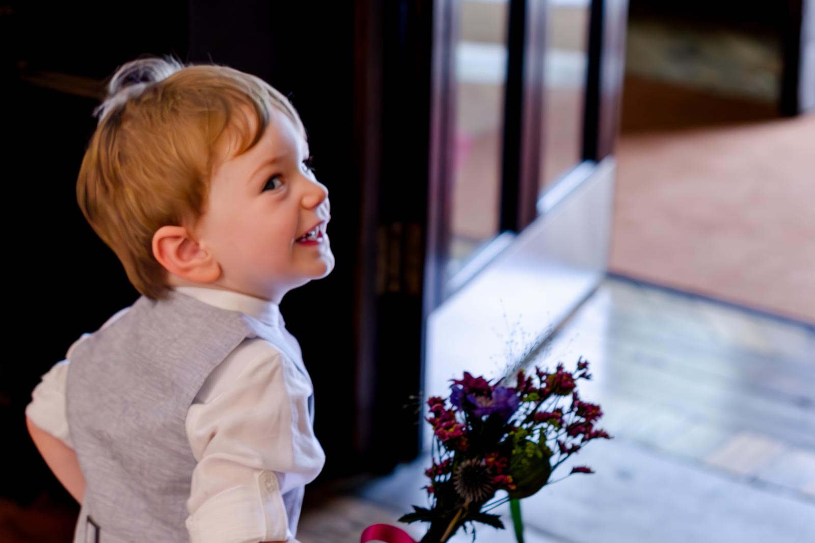 Katherine and Ben's young son smiles as he runs through Lewes Register Office before the couples wedding.