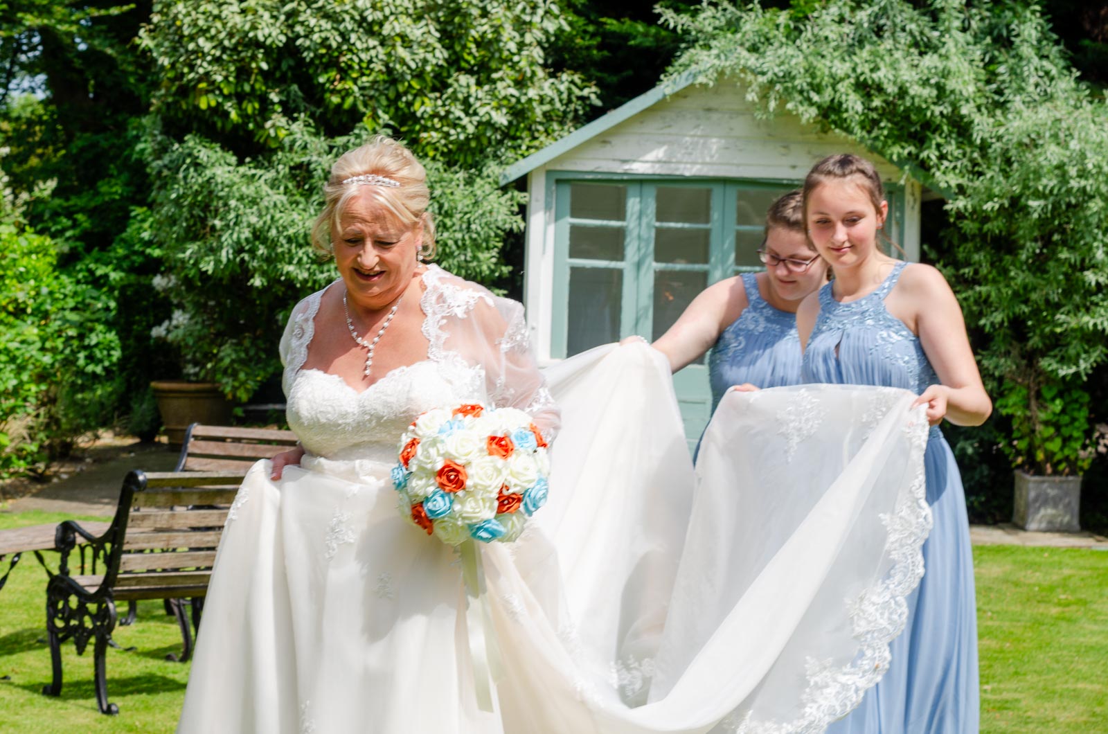 Bridesmaid's carry Wendy's train in the garden's at The Shelley's Hotel in Lewes.