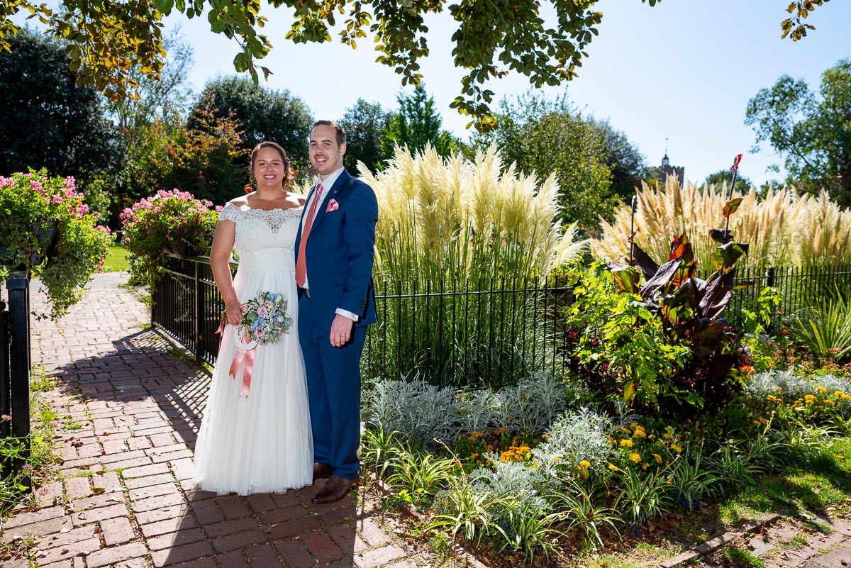 Amy and James pose in the blooming beds of Southover Grange after their wedding.