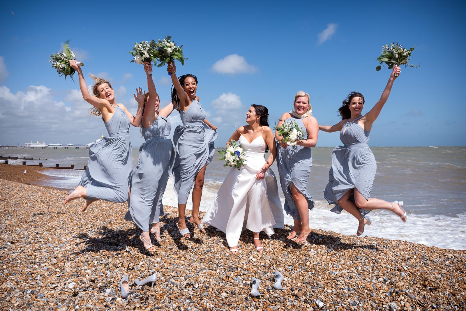Jane's bridesmaids jump in the air on Eastbourne Beach after her wedding to Ally at Grand Hotel. 
