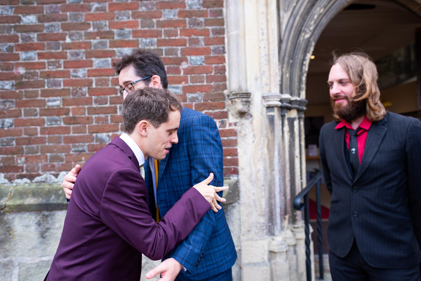 Ashley hugs his best man at the front entrance of Trinity Church in Lewes before his wedding to Anjana.