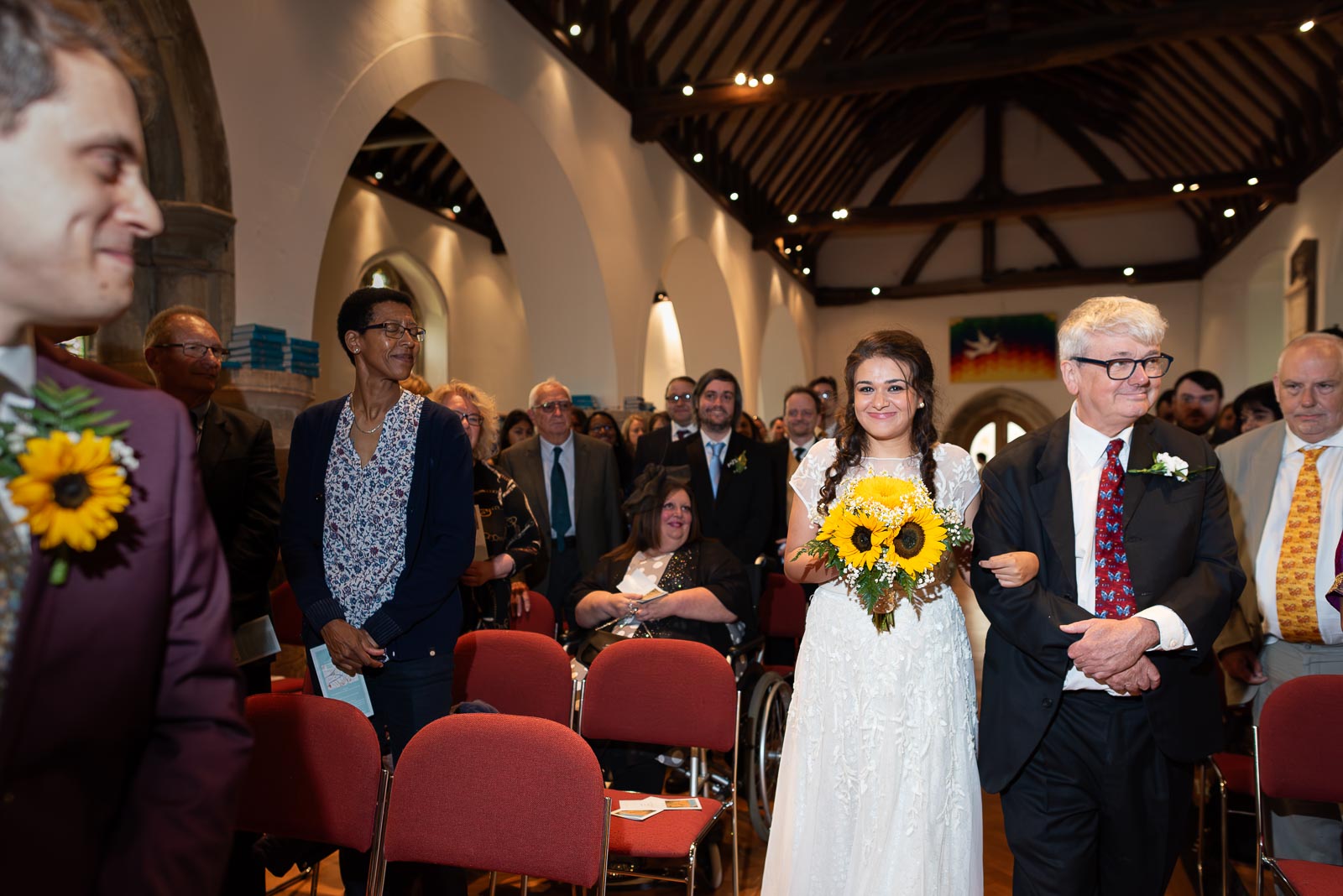 Ashley smiles as Anjana arrices at the top of the aisle  with her day before their wedding at Trinity Church in Lewes.