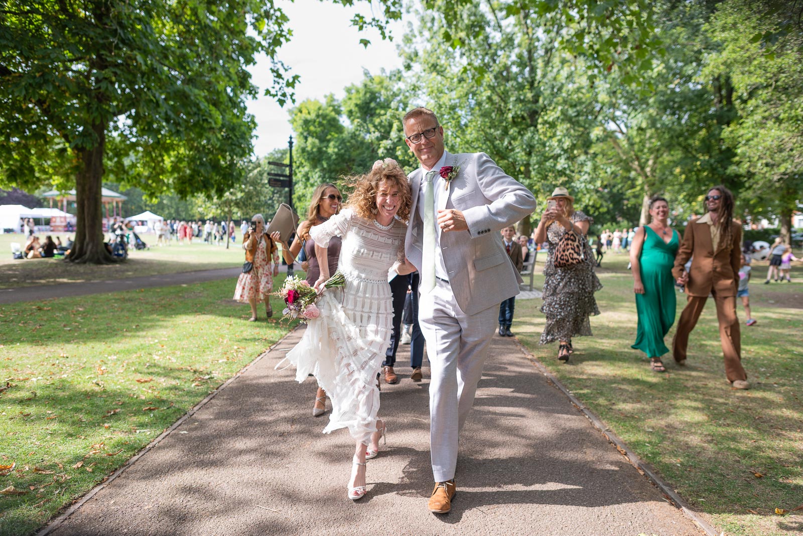 Kitty and Will dance to the wedding venue after their wedding in the Band Stand at Queens Park in London.