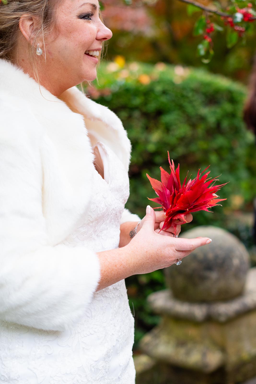Laura holds some Autumnal red leaves in Southover Grange, Lewes after her wedding to Sam.