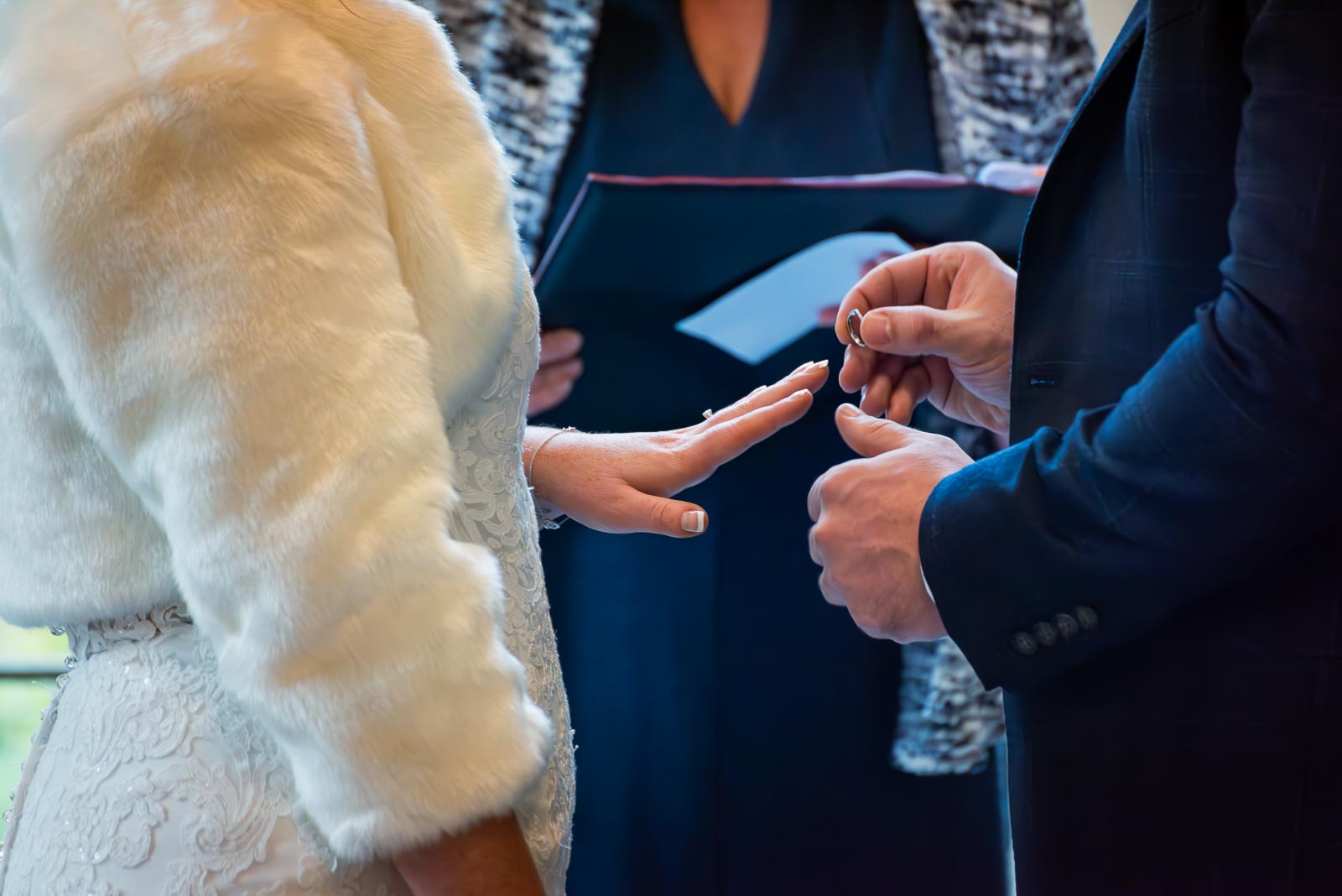 Sam places a wedding ring on Laura's finger at the top of the aisle in the Ainsworth Room in Lewes Register Office during their wedding.