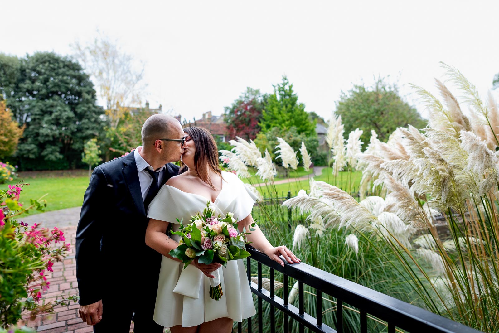 Maria and Robert embrace on a bridge in Southover Grange, Lewes after their wedding. 