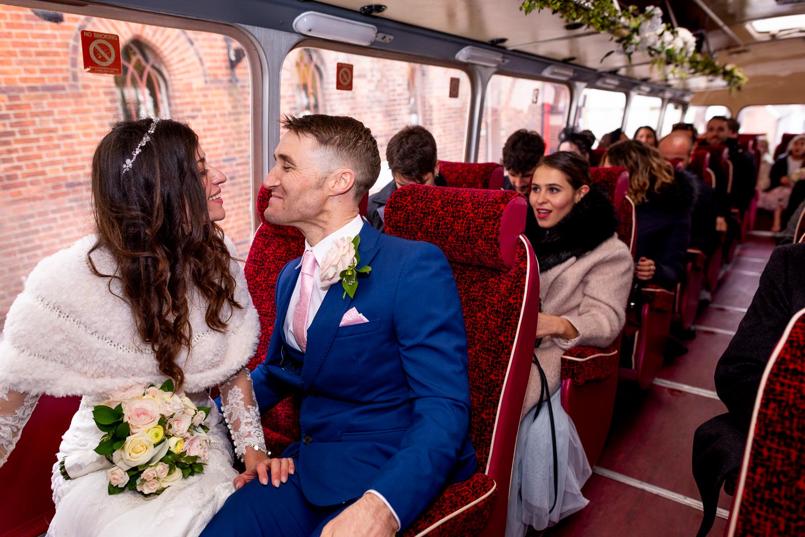 Virginia and Simon exchange a look in the bus journey with their guests to their Wedding Reception at Horsted Place.