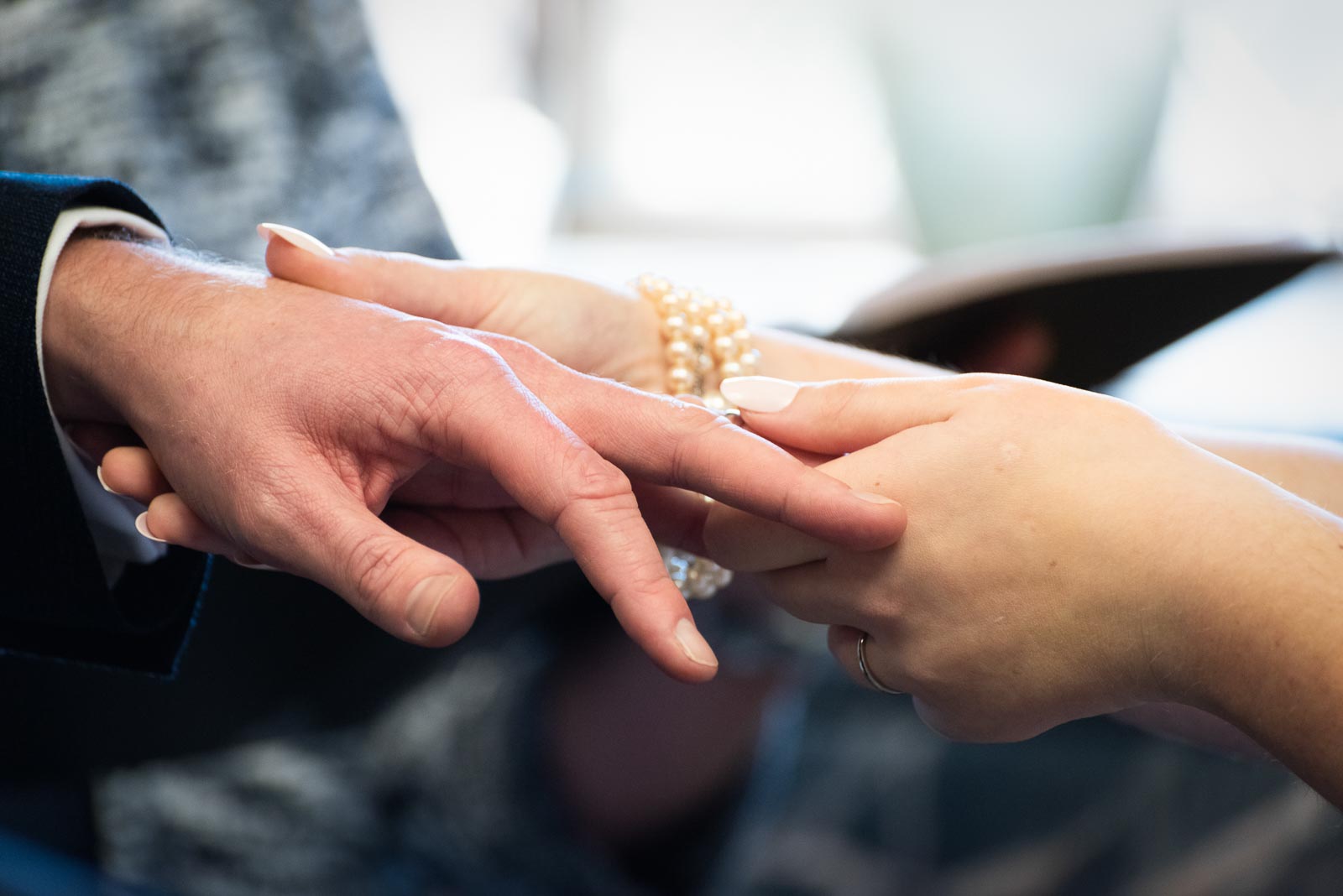 A close up of Chris putting the wedding ring on Belinda's hand in the Evelyn Room at Lewes Register Office during their wedding.