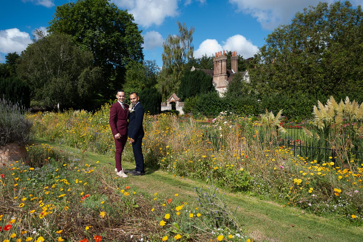 Ady and Jose stand among the Summer blooms at Southover Grange with Lewes Registry Office in the background.