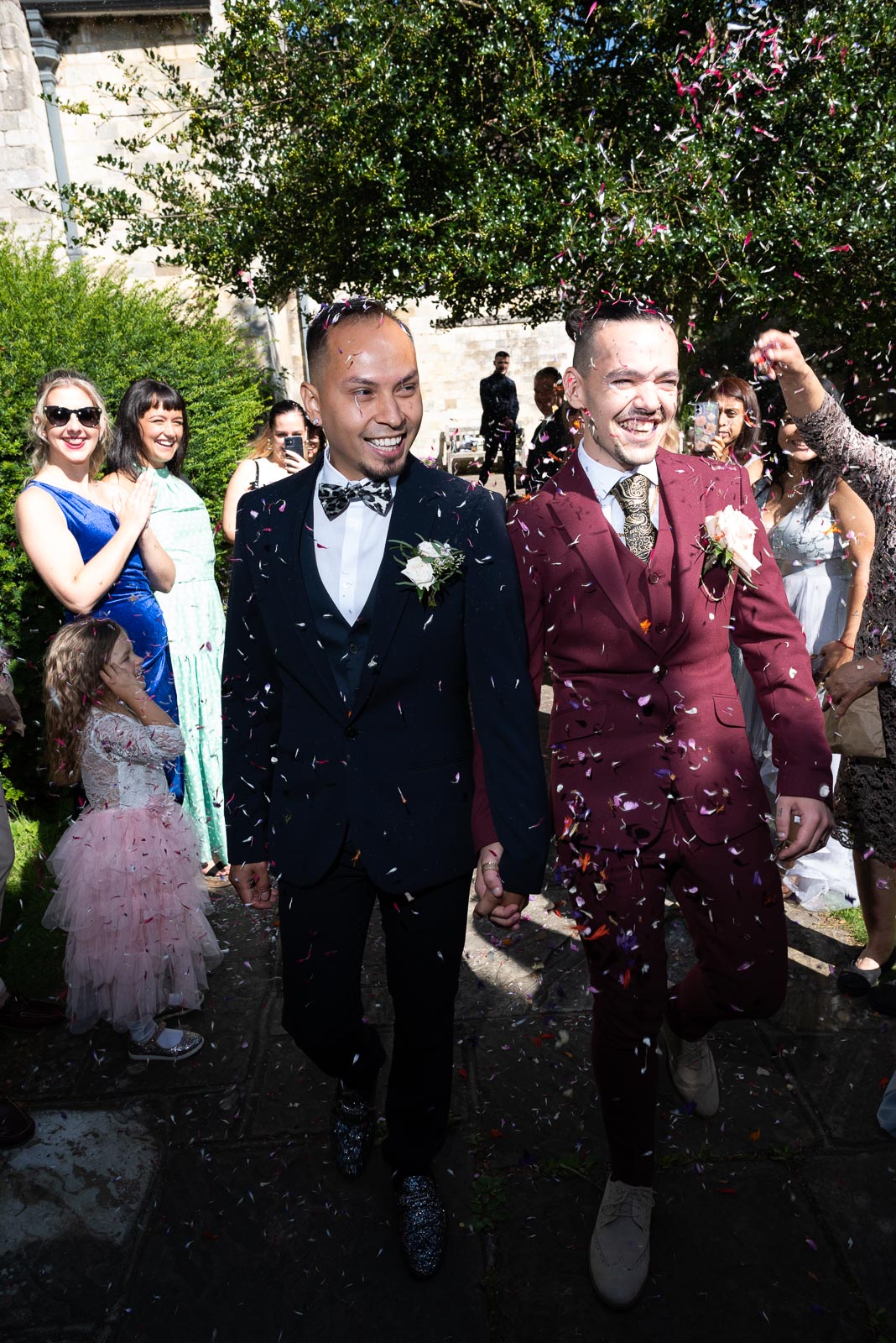 Ady and Jose walk through confetti thrown by their wedding guests in Southover Grange, Lewes.