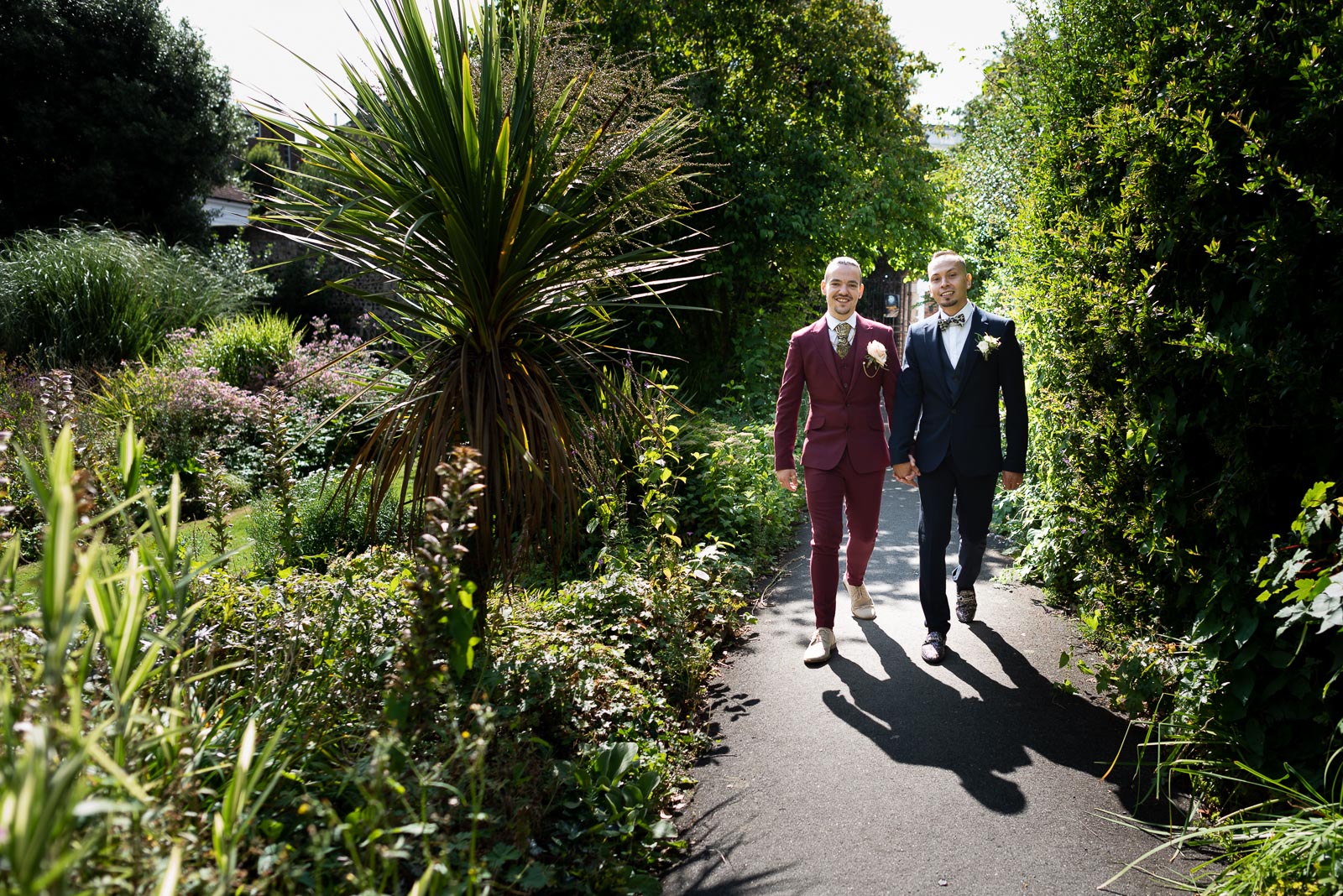 Ady and Jose walk through Southover Grange after their wedding in Lews Registry Office backlit by Summer sun. 