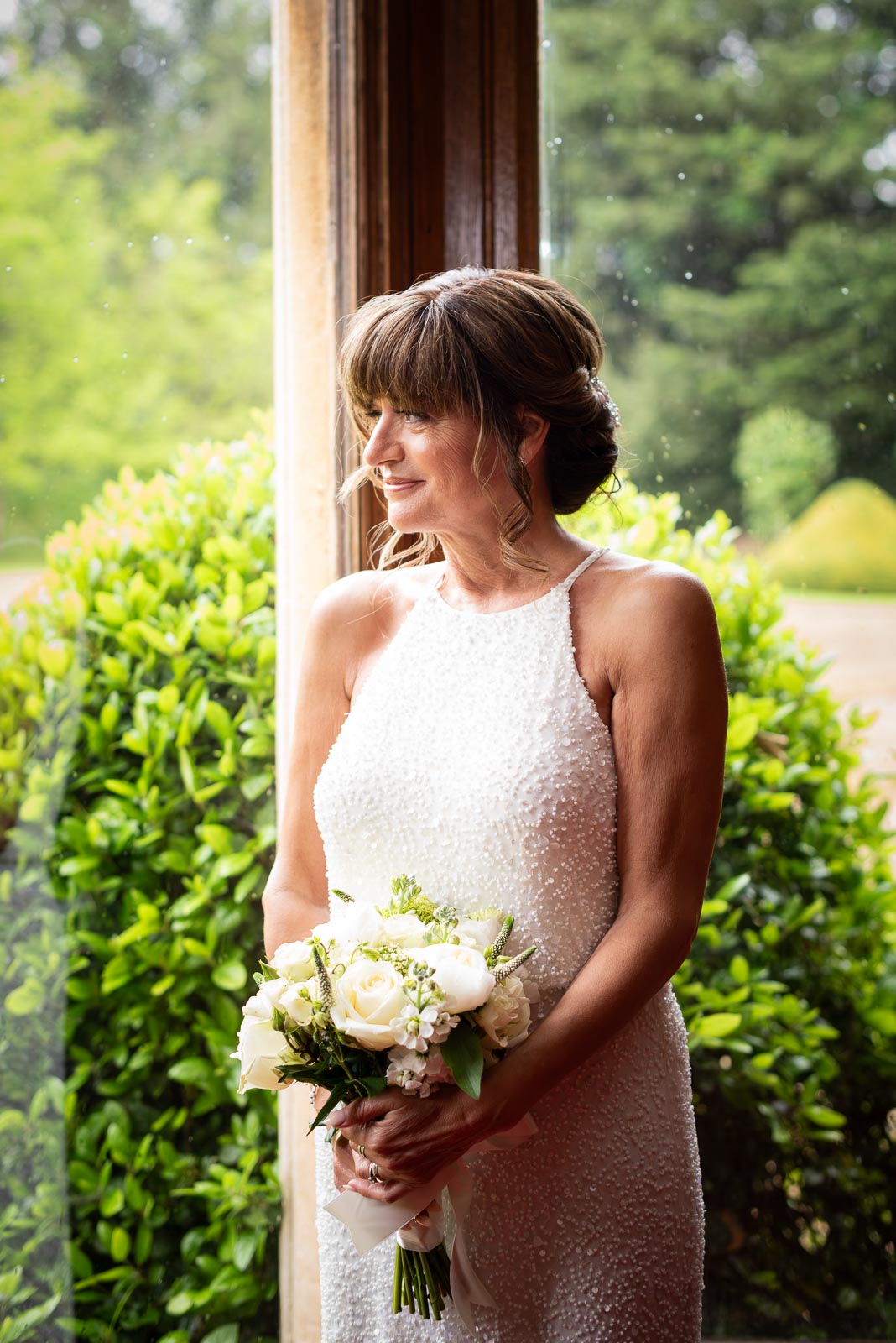 Carmen poses at a bay window after her wedding to jeff in Manor by the Lake in Cheltenham.