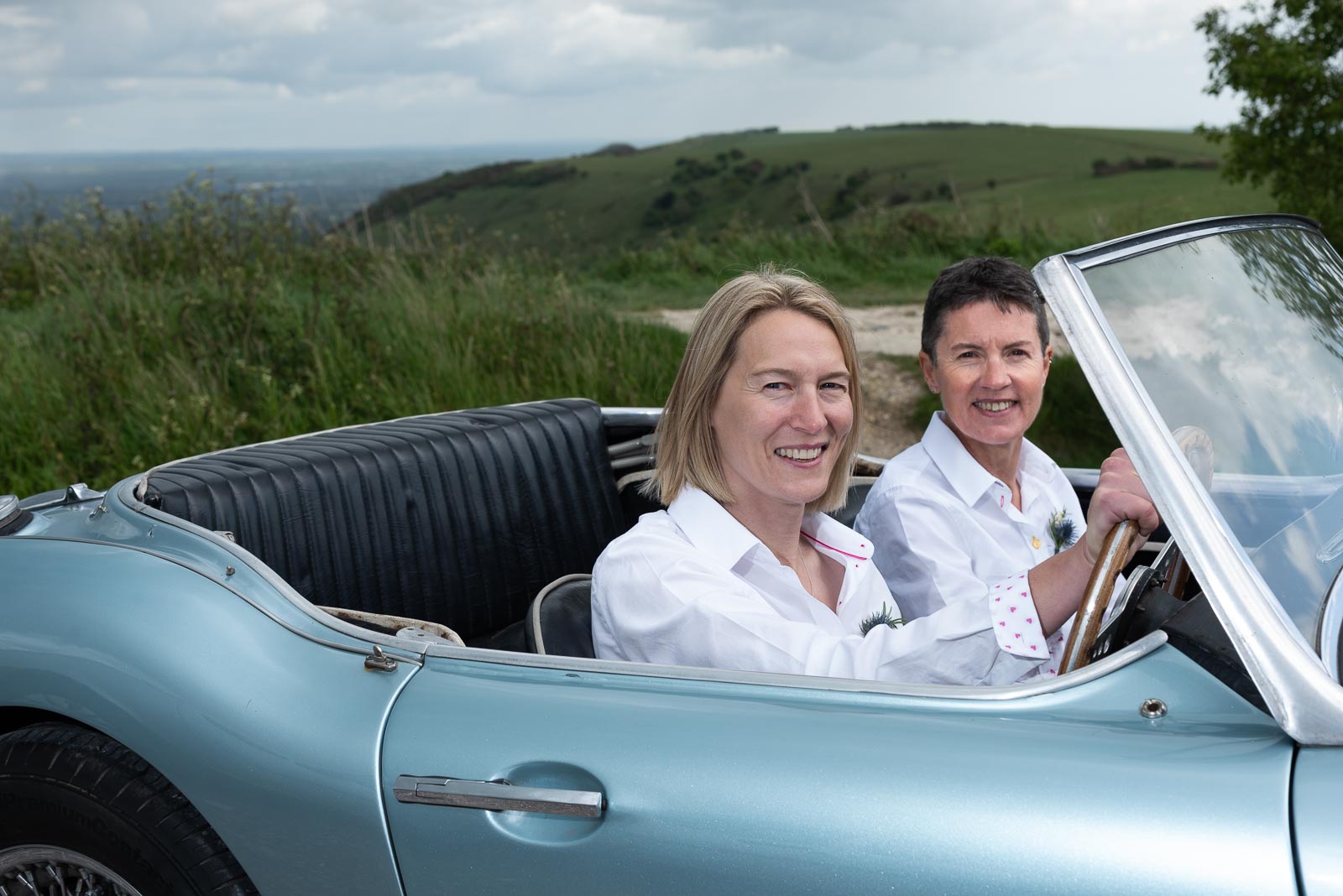 Kate and Sam pose next in their wedding car at Ditchling Beacon.