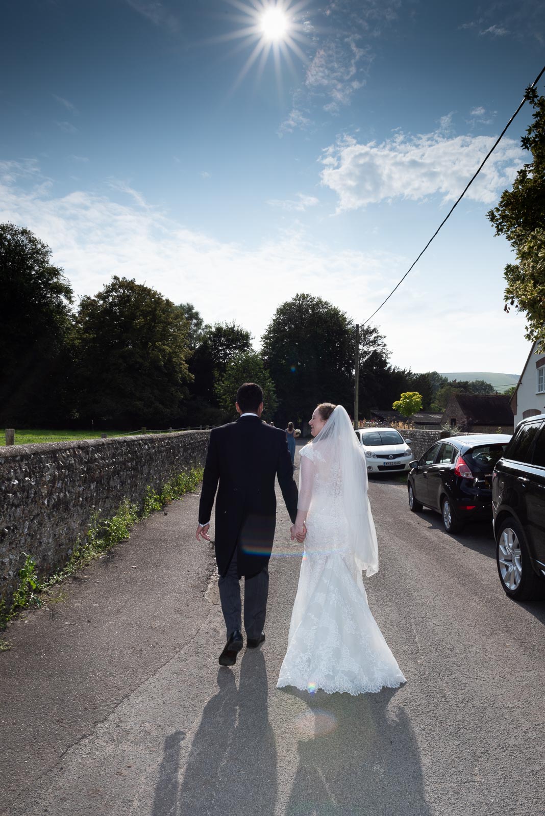 Lily and Callum walk back to the family home after getting married at St Nicholas Church in Iford.