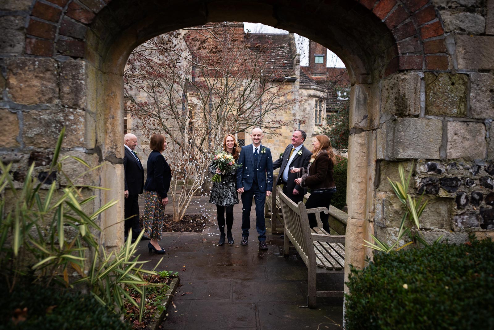 Melanie and Ryan are pictured through one of the arches in Southover Grange after their wedding in the Evelyn Room at Lewes Register Office.