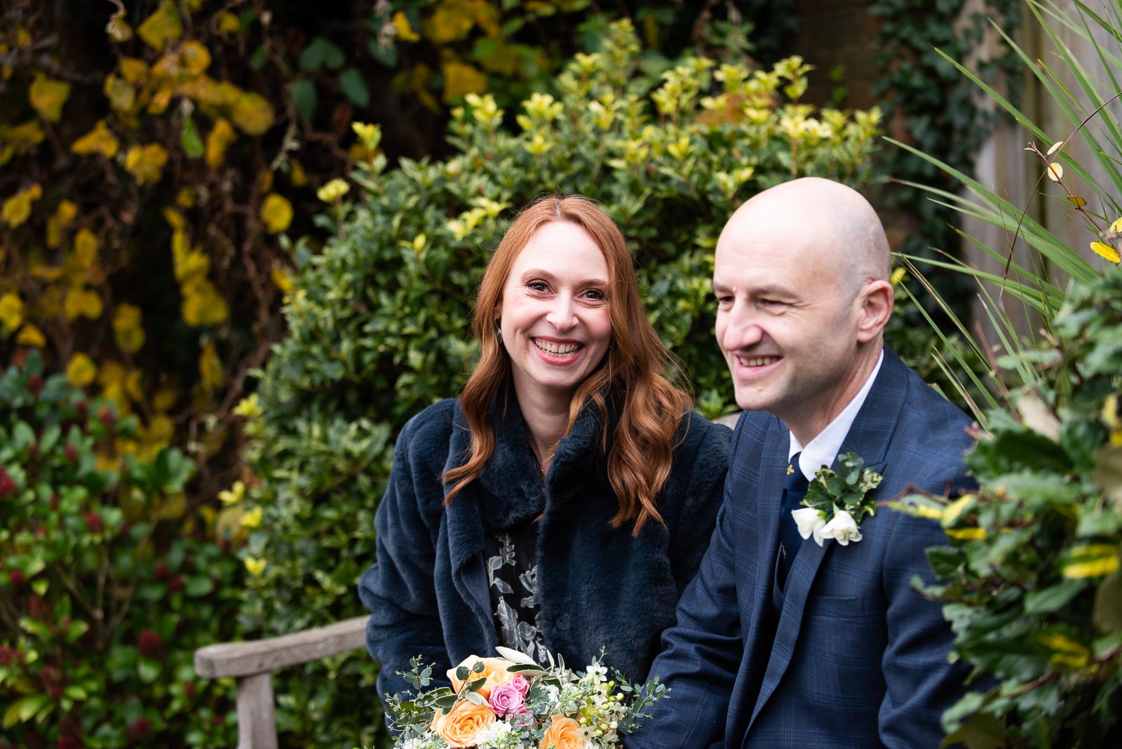 Melanie and Ryan smile on a bench in Southover Grange after their wedding at Lewes Register Office.