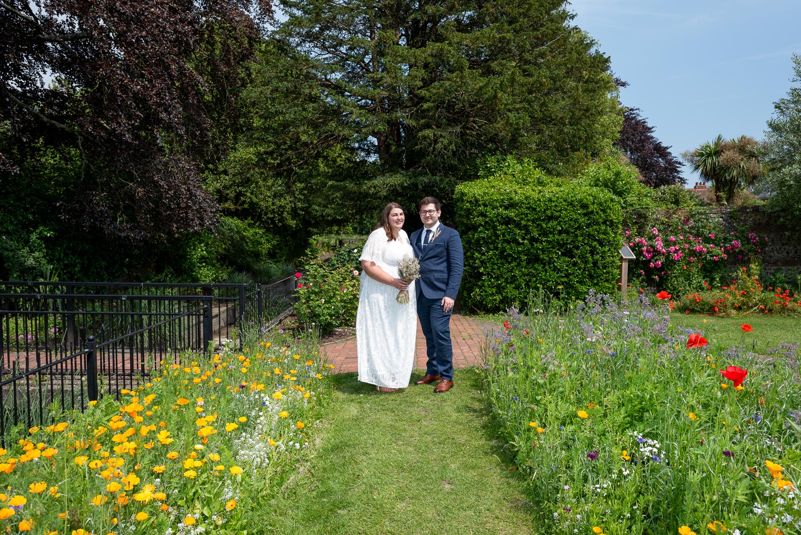 Sophie and Nathan pose inbetween the Summer blooms in Southover Grange after their wedding in Lewes Register Office.