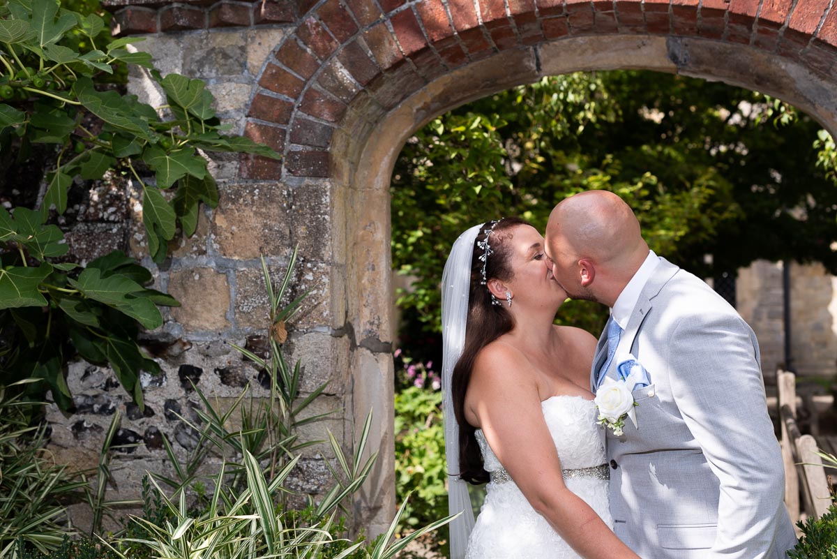 Soraya and Billy embrace on front of one of the arches in Southover Grange after their wedding at Lewes Register Office.