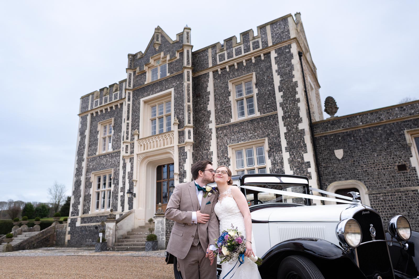 Lewis kisses Stephanie on the cheek next to their wedding car outside Folkington Manor near Polegate.