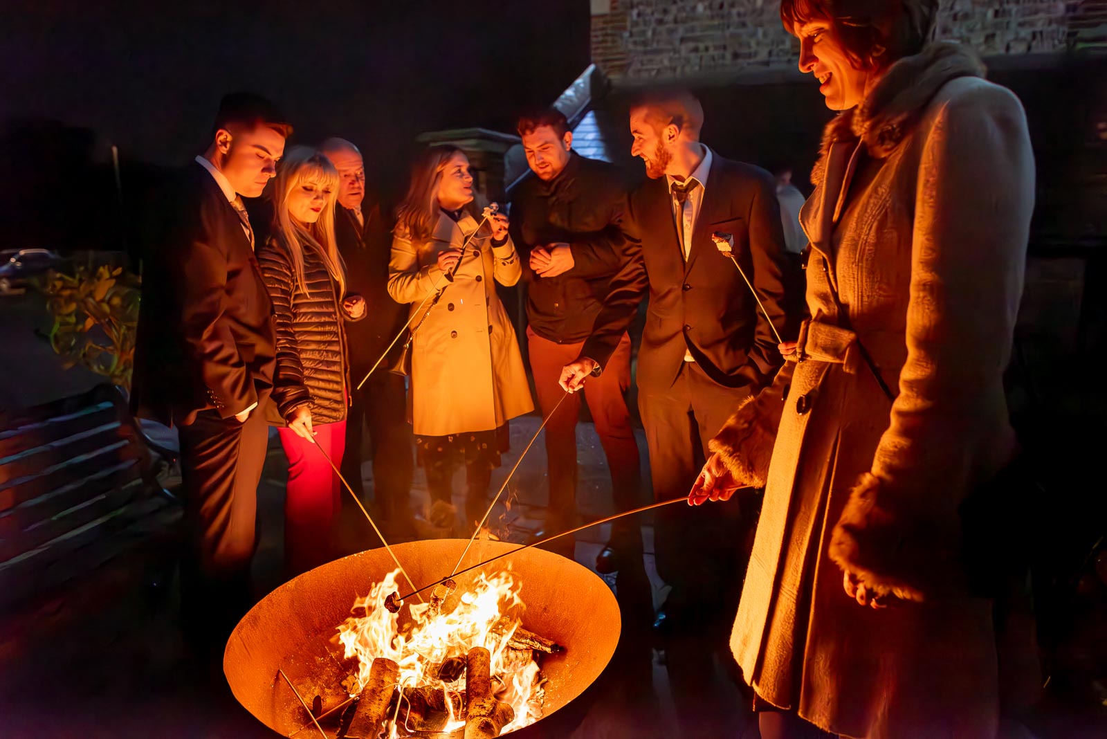 Wedding guests enjoy toasting some marshmallows in the courtyard at Folkington Manor near Polegate.