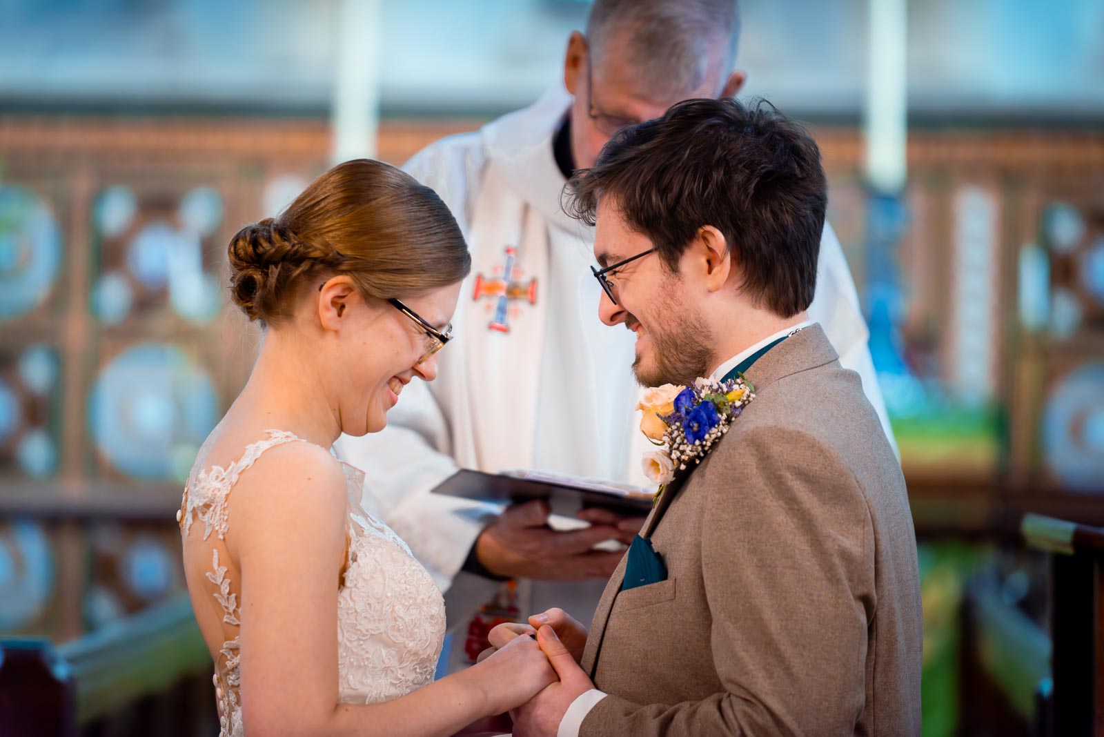 Stephanie and Lewis enjoy a funny moment whilst exchanging rings at their wedding in The Church of St Peter and St Paul in Hellingly. 