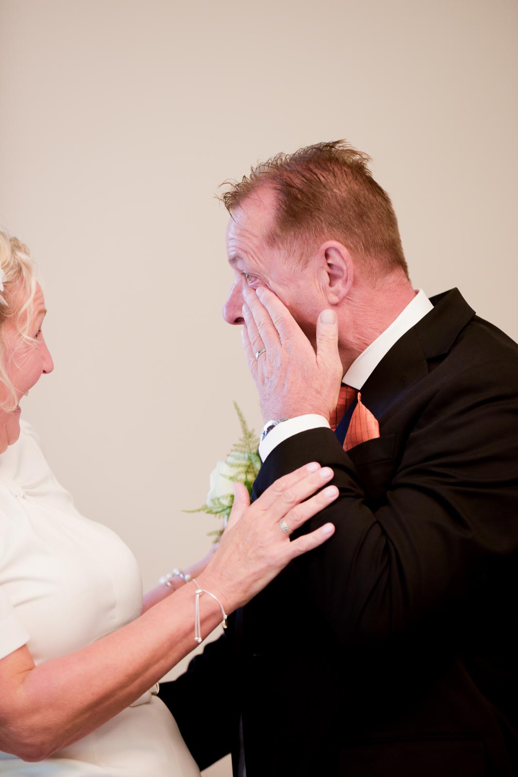 Martin rubs a tear away from his eye whilst Joanne gives him a reassuring look during their wedding in the Evelyn Room at Lewes Register Office.