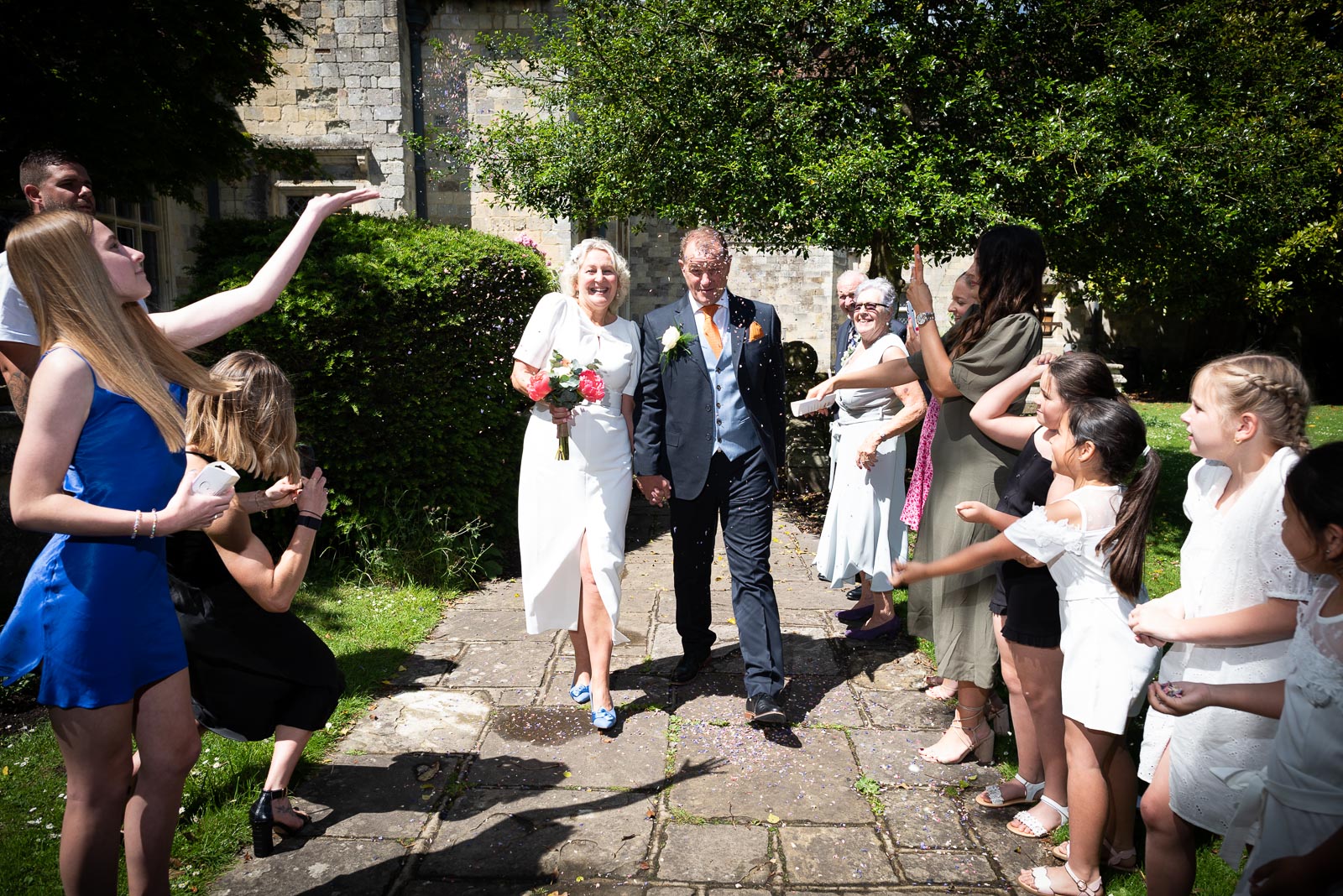 Martin and Joanne walk through confetti thrown by friends and family in Southover Grange after their wedding. 