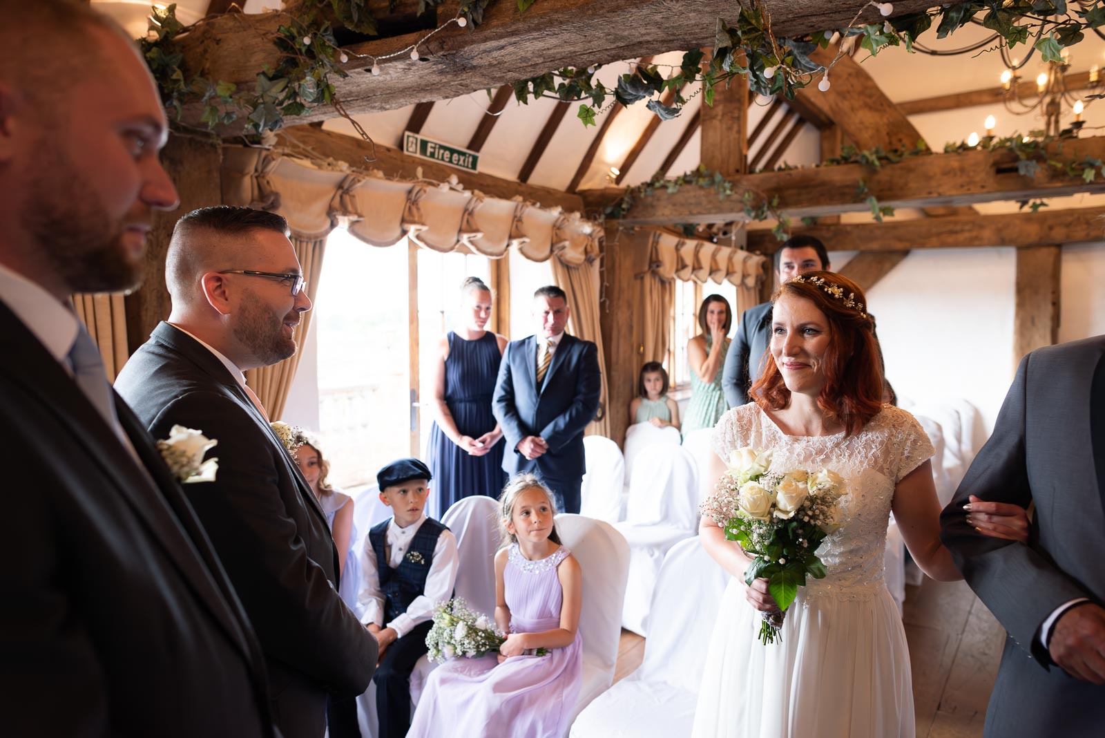 Adrienn arrives at the top of the aisle at Milwards Farm Estate near Lewes with Lee and his best man smiling. 