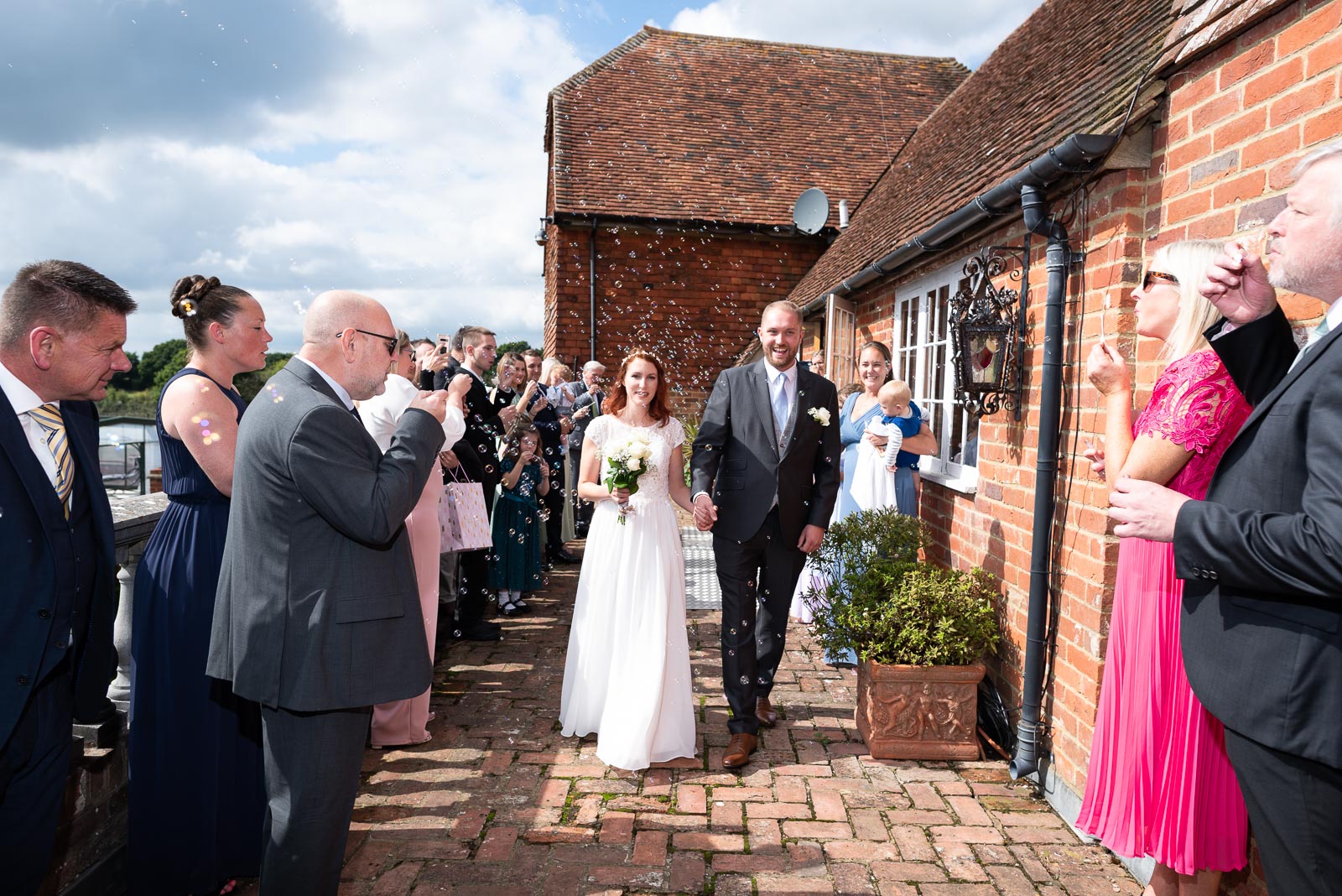 Adrienn and Lee walk through confetti outside Milwards Farm Estate near Lewes after getting married.