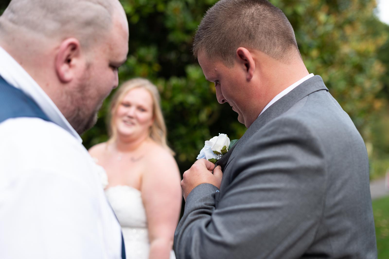 Jacob and his best man check his Wedding pin in Southover Grange, Lewes after marrying Eliana who is in the background. 