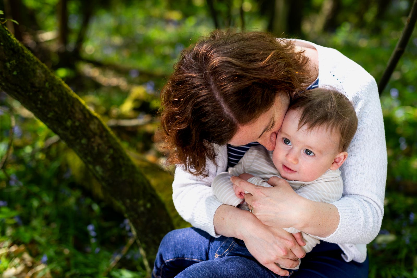 Alexis gives eight month old baby Alasdair a hug and a kiss among the bluebells at Battle Great Woods.