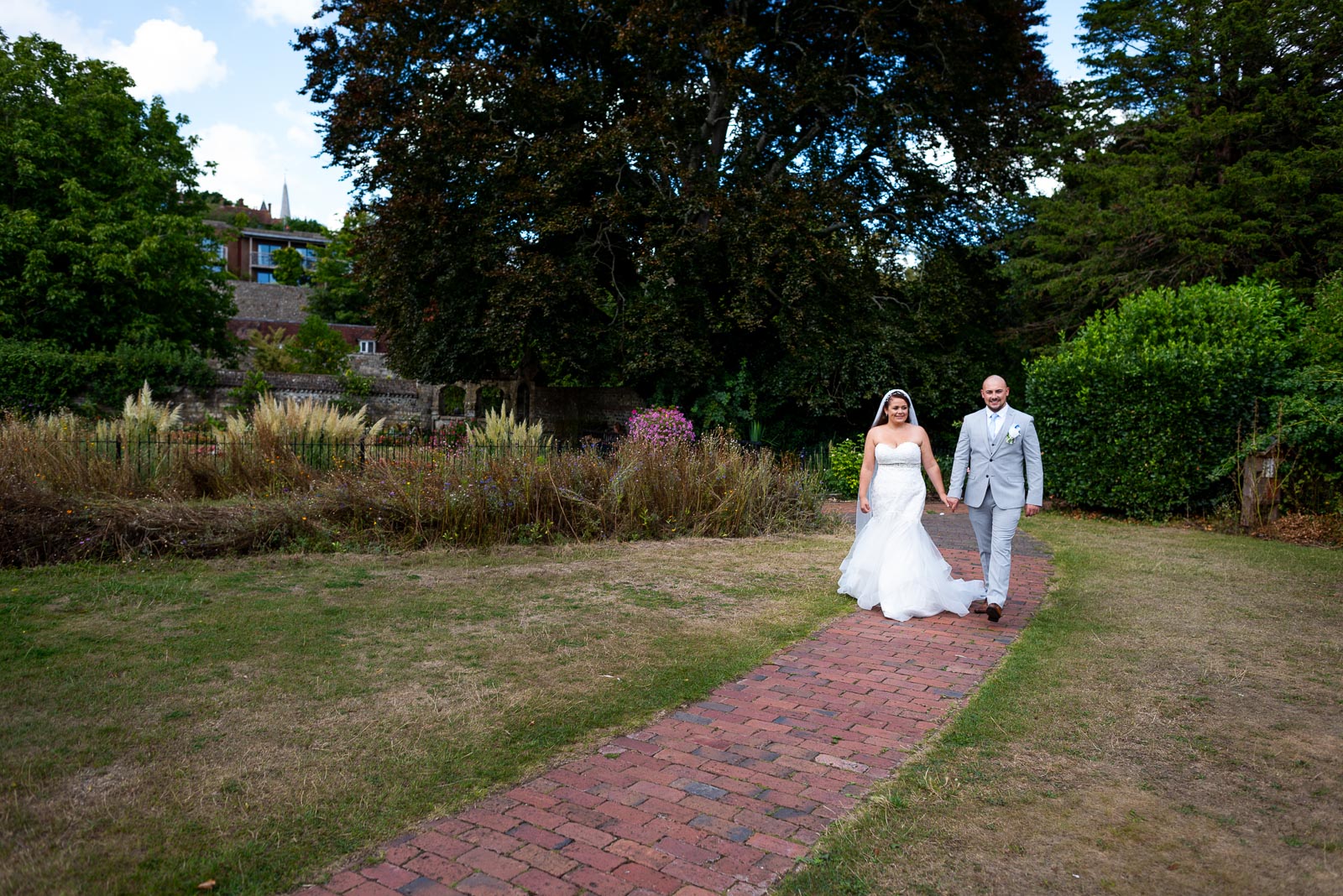 Soraya and Billy walk down a red brick path in Southover Grange, Lewes after their wedding.