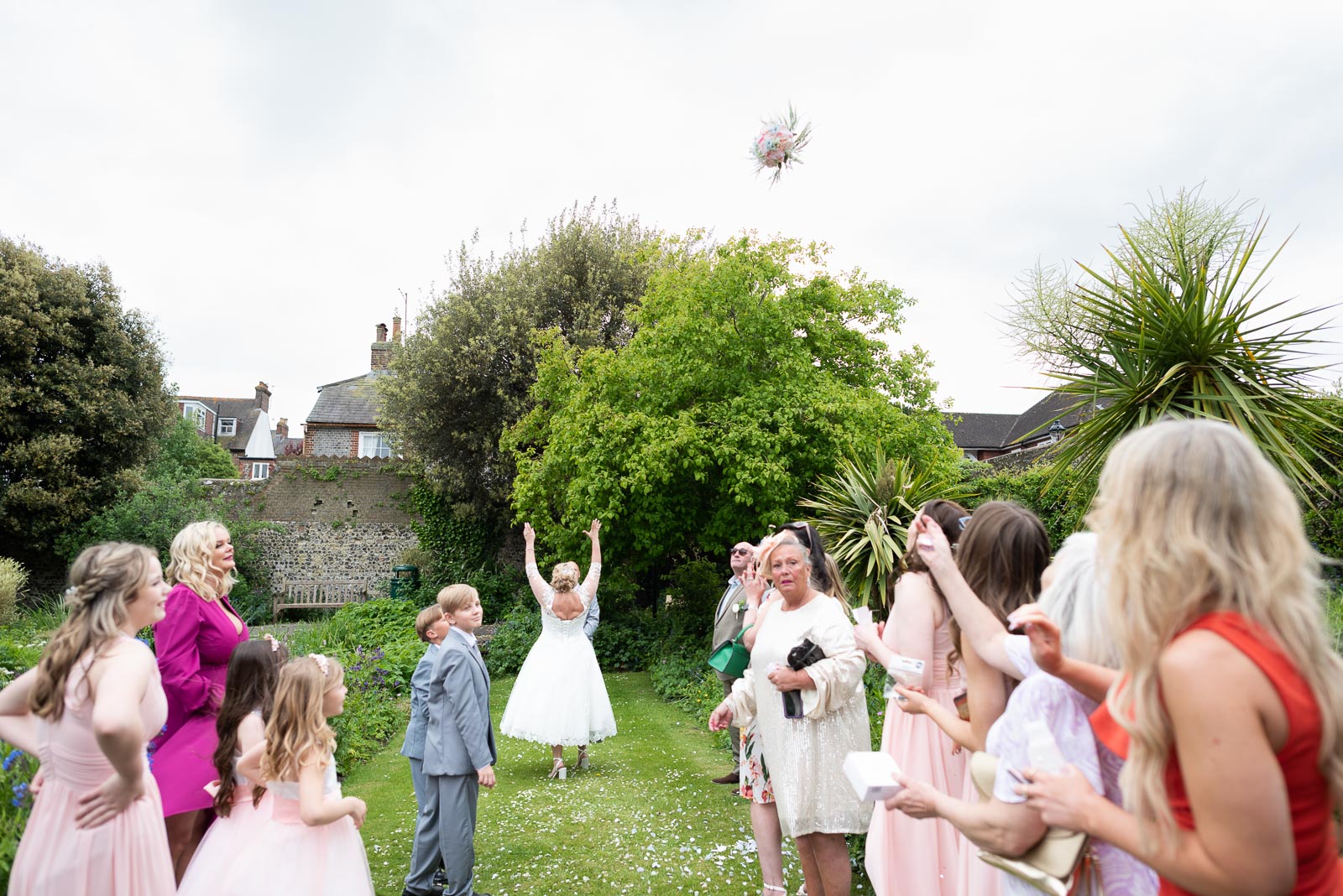 Lou throws her bouquet into friends and family at at Southover Grange Lewes after marrying Matt,