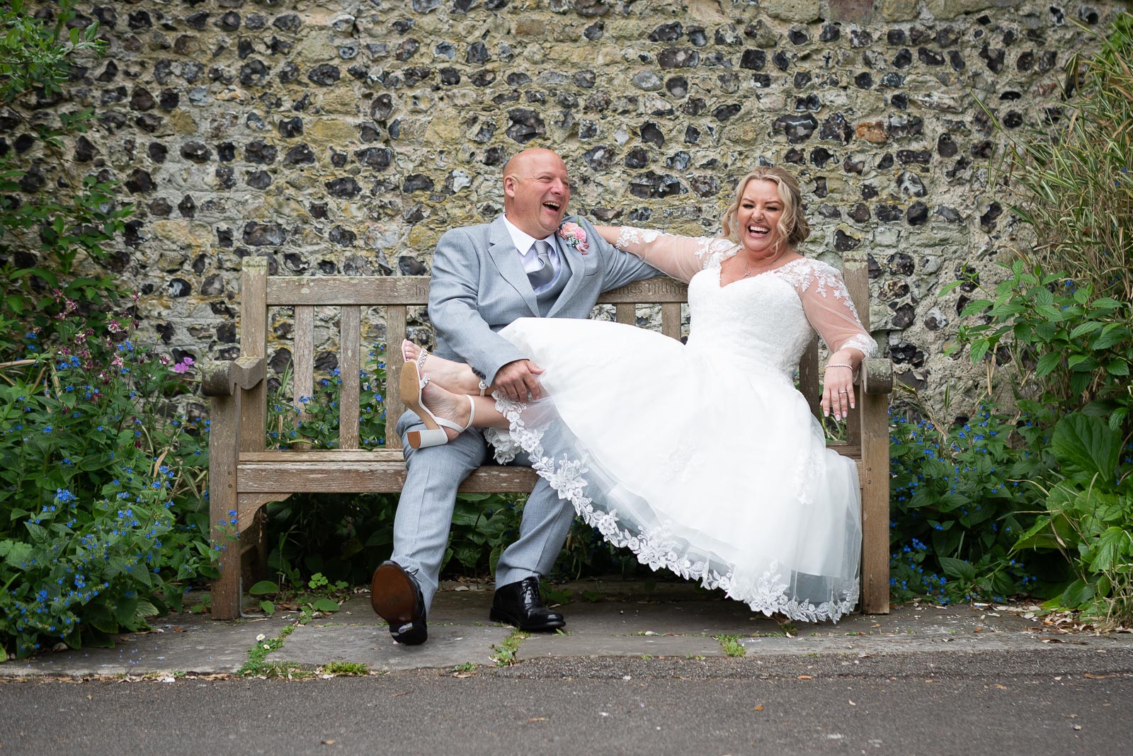 Lou and Matt enjoy a funny moment whilst sitting on a bench at Southover Grange after getting married at Lewes Register Office.