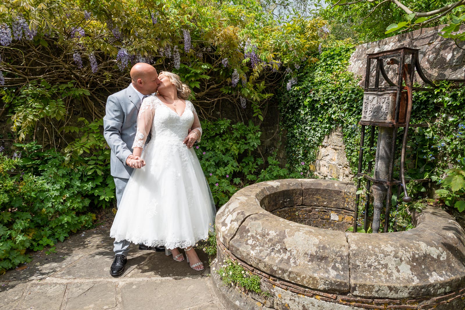 Lou and Matt embrace next to an ancient well in Southover Grange after getting married at Lewes Register Ofiice.