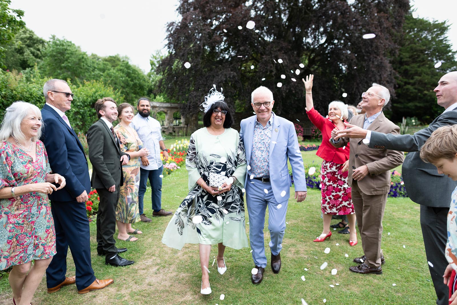 Ashifa and Julian walk through confetti thrown by their friends and family in Southover Grange in Lewes