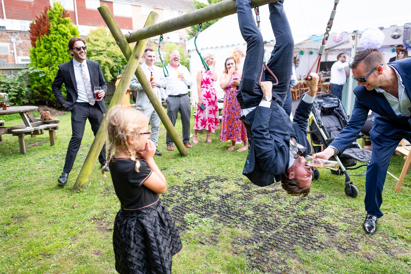 Guests enjoy a moment on the climbing frame at May and Marks Wedding Reception in the garden of the Anchor Inn in Ringmer