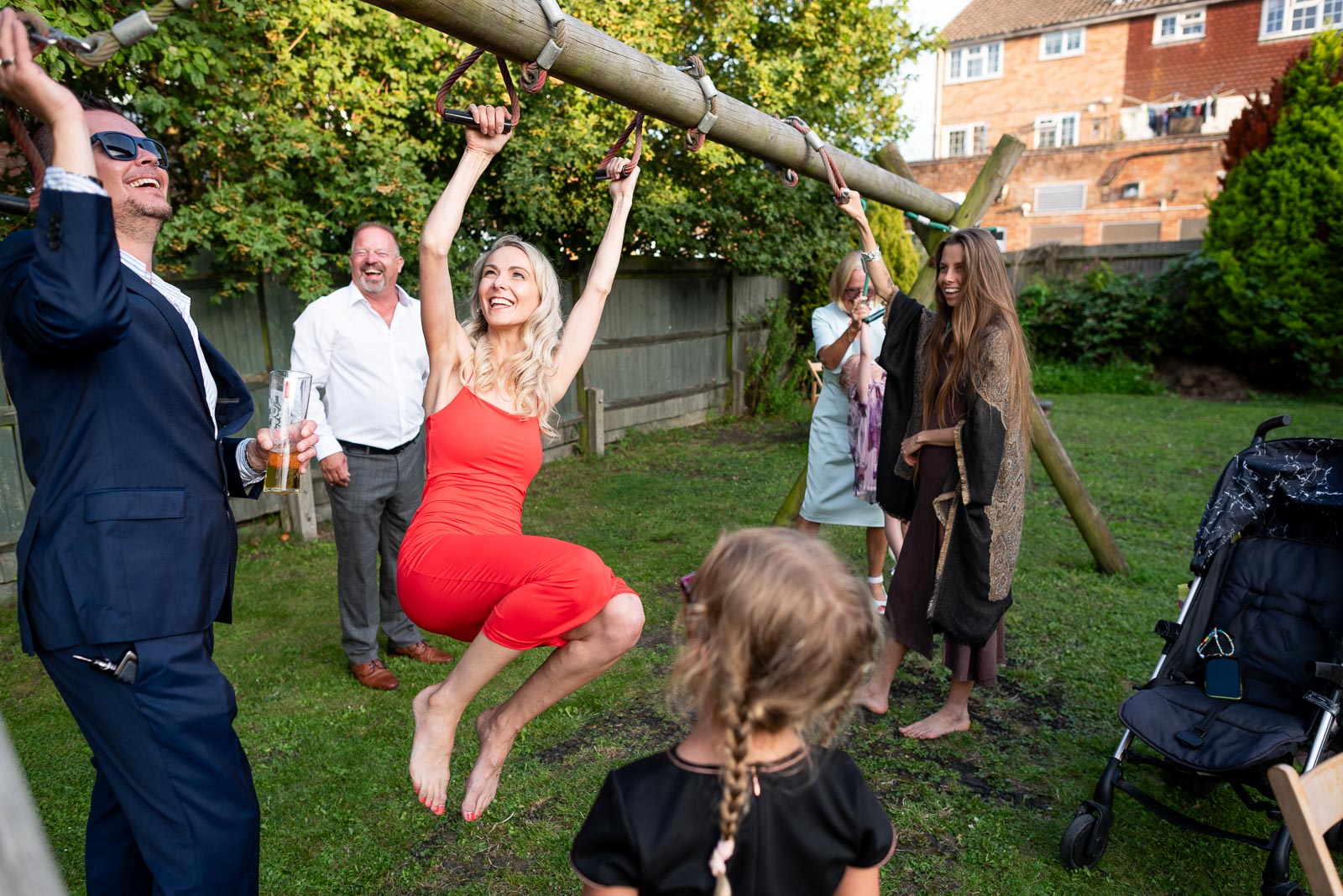 Guests enjoy a moment on the climbing frame at May and Marks Wedding Reception in the garden of the Anchor Inn in Ringmer