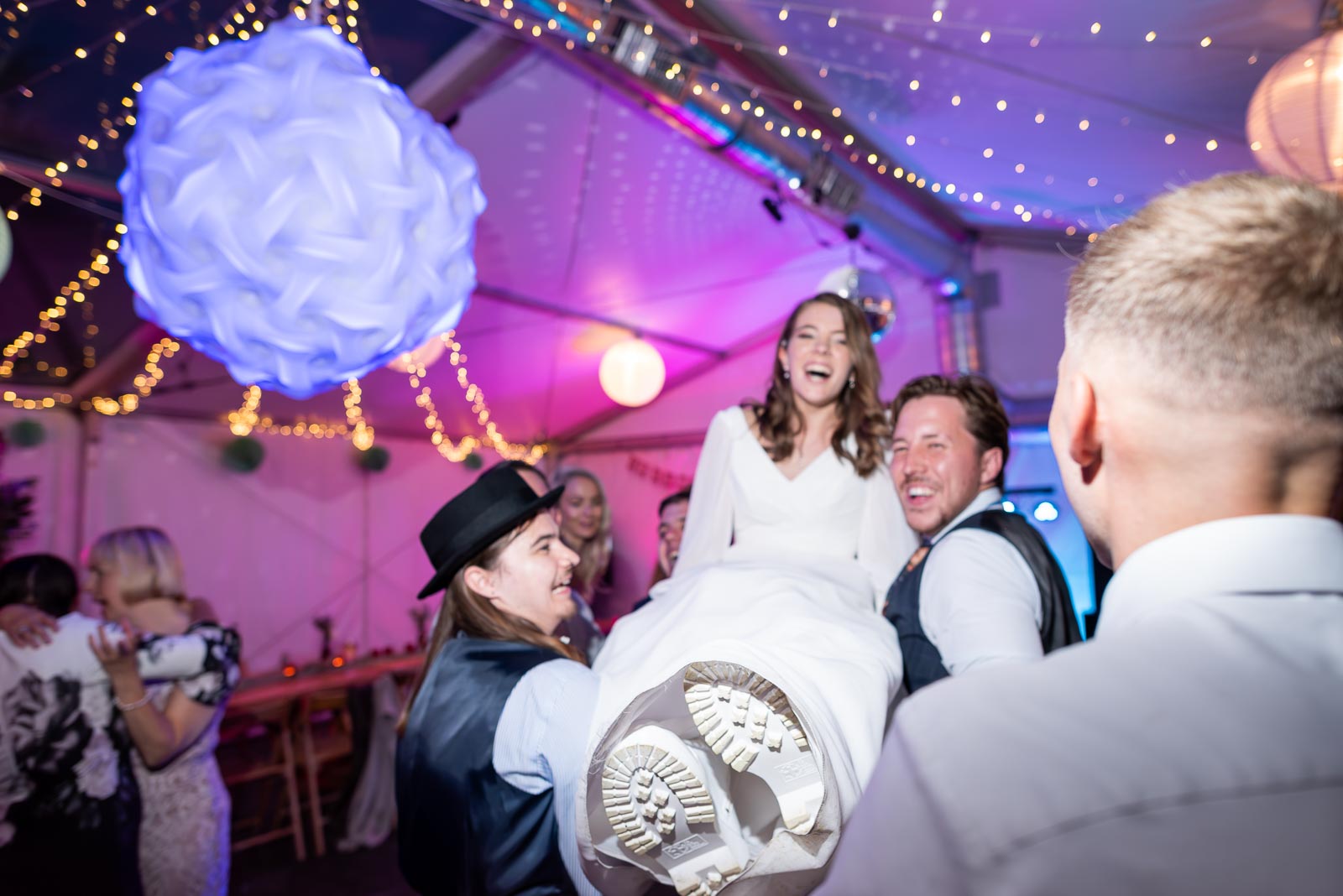 May is lifted on a chair by friends and family at Mark and her Wedding Reception in the Anchor Inn in Ringmer